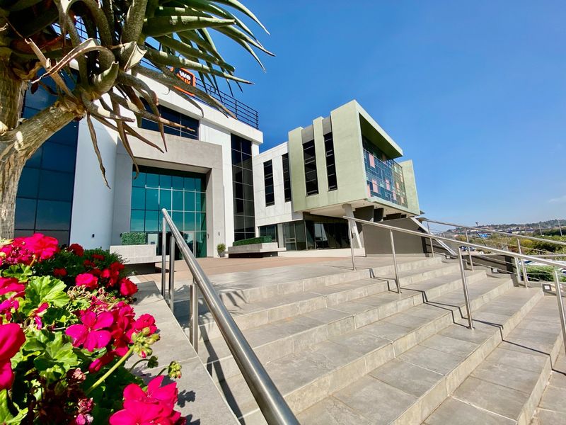 Modern commercial building exterior featuring a prominent tiled staircase, glass facade, and contemporary architectural design with stainless steel handrails.