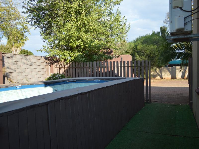 Outdoor area featuring an above-ground swimming pool with timber decking, artificial grass, and perimeter fencing.