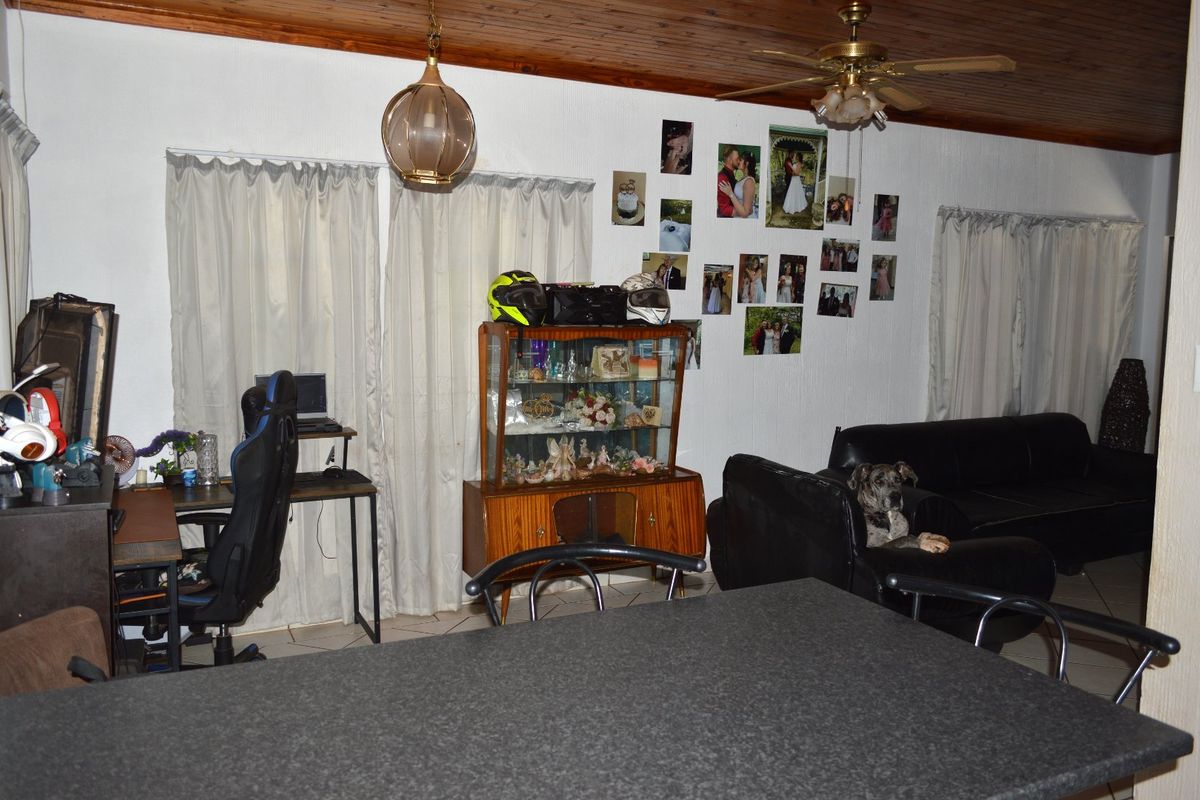 A living area featuring a timber tongue and groove ceiling, ceiling fan, and tiled flooring.