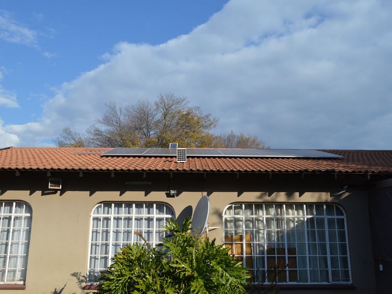 Rear exterior view of the house featuring a tiled roof with installed solar panels and large steel-framed windows.