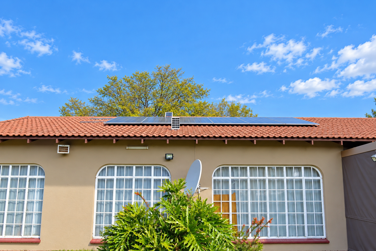 Rear exterior view of the house featuring terracotta roof tiles, installed solar panels, and arched windows with white frames.