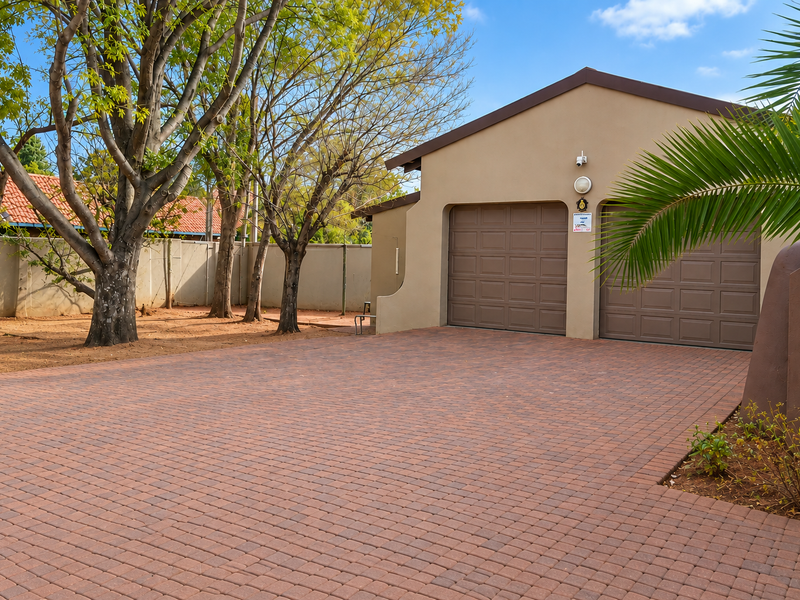 A well-maintained double garage with a paved driveway and secure perimeter walling, set in a neat residential garden environment.