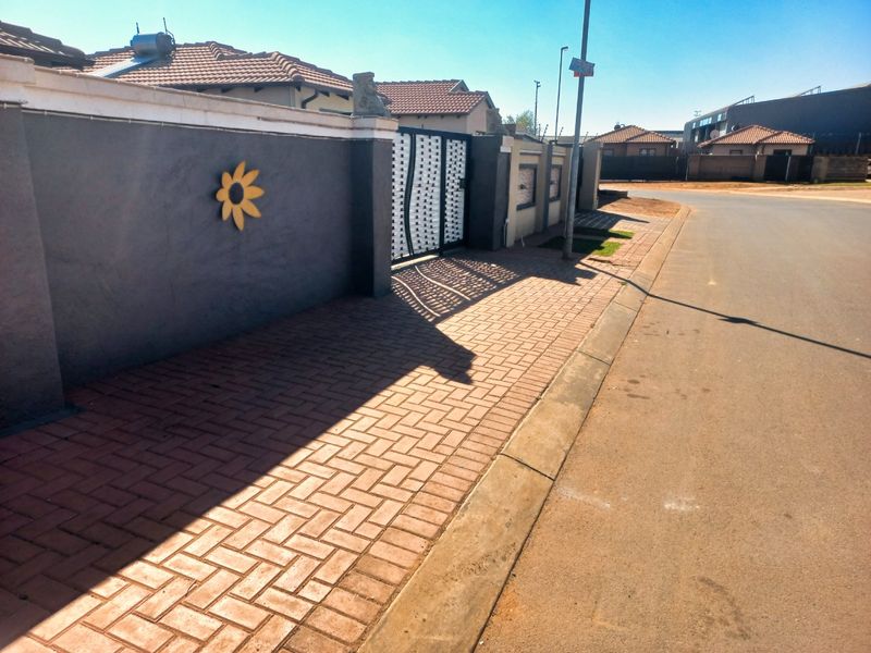 Street view showing the property's perimeter wall, paved sidewalk, and gated entrance in a residential neighbourhood.