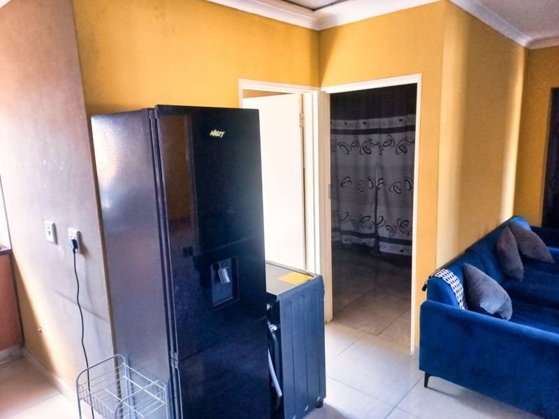 A living area featuring tiled flooring and coved ceilings, showing signs of wear on the walls and requiring cosmetic updates.