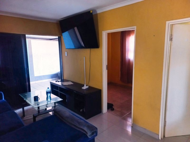 Living room featuring tiled flooring, sliding glass door access to the patio, and direct access to an adjacent room.