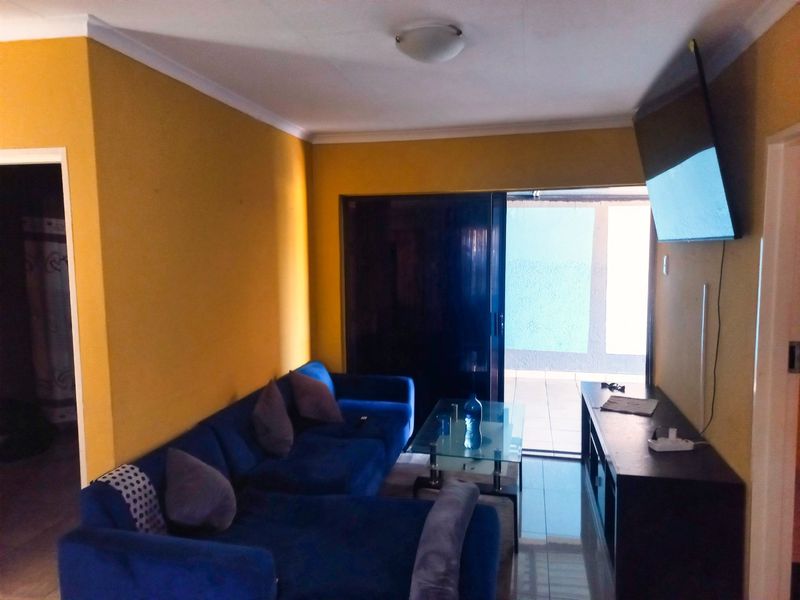 A living room featuring tiled flooring, cove cornicing, and a sliding glass door providing access to an outdoor area.