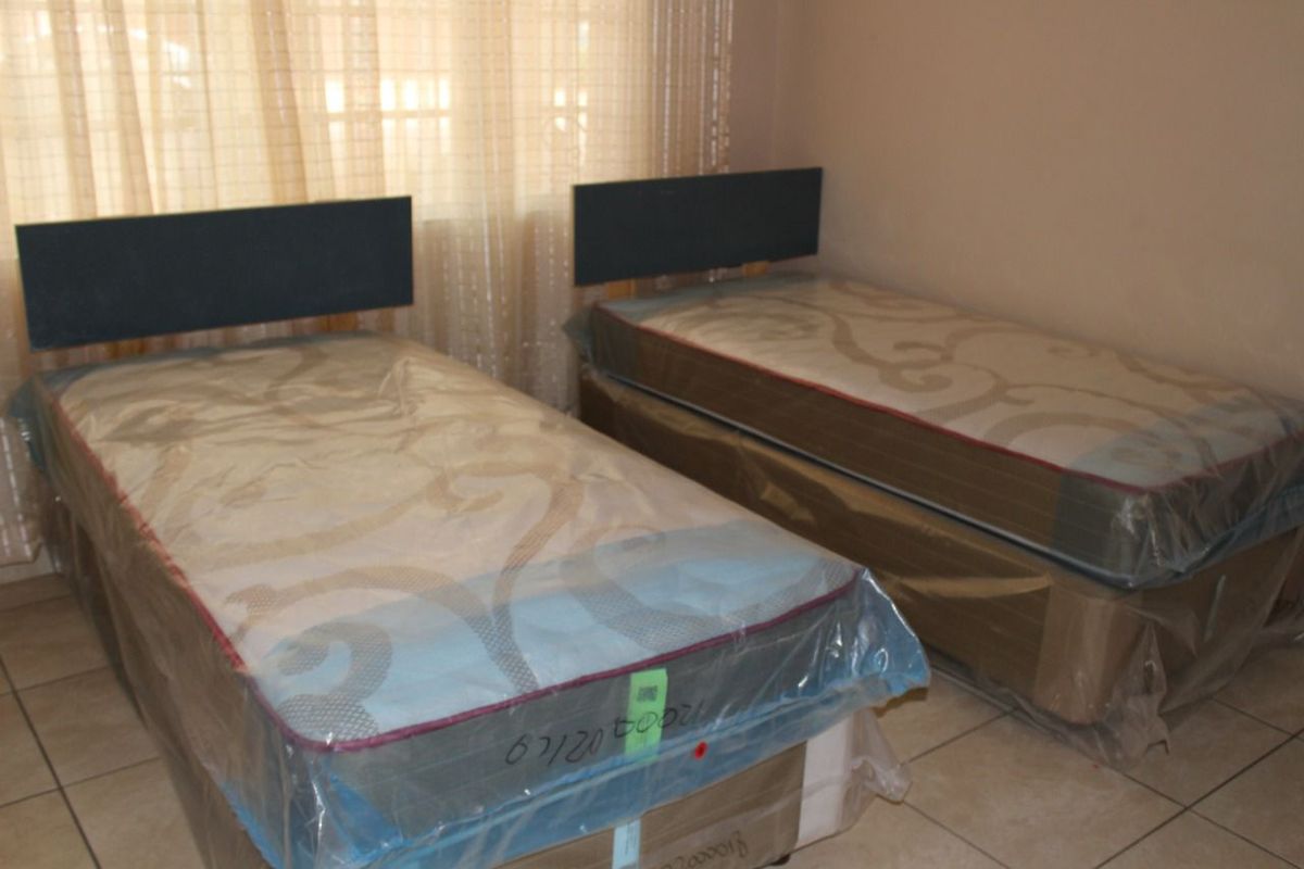 A bedroom featuring tiled flooring and neutral wall finishes, currently set up with twin beds.