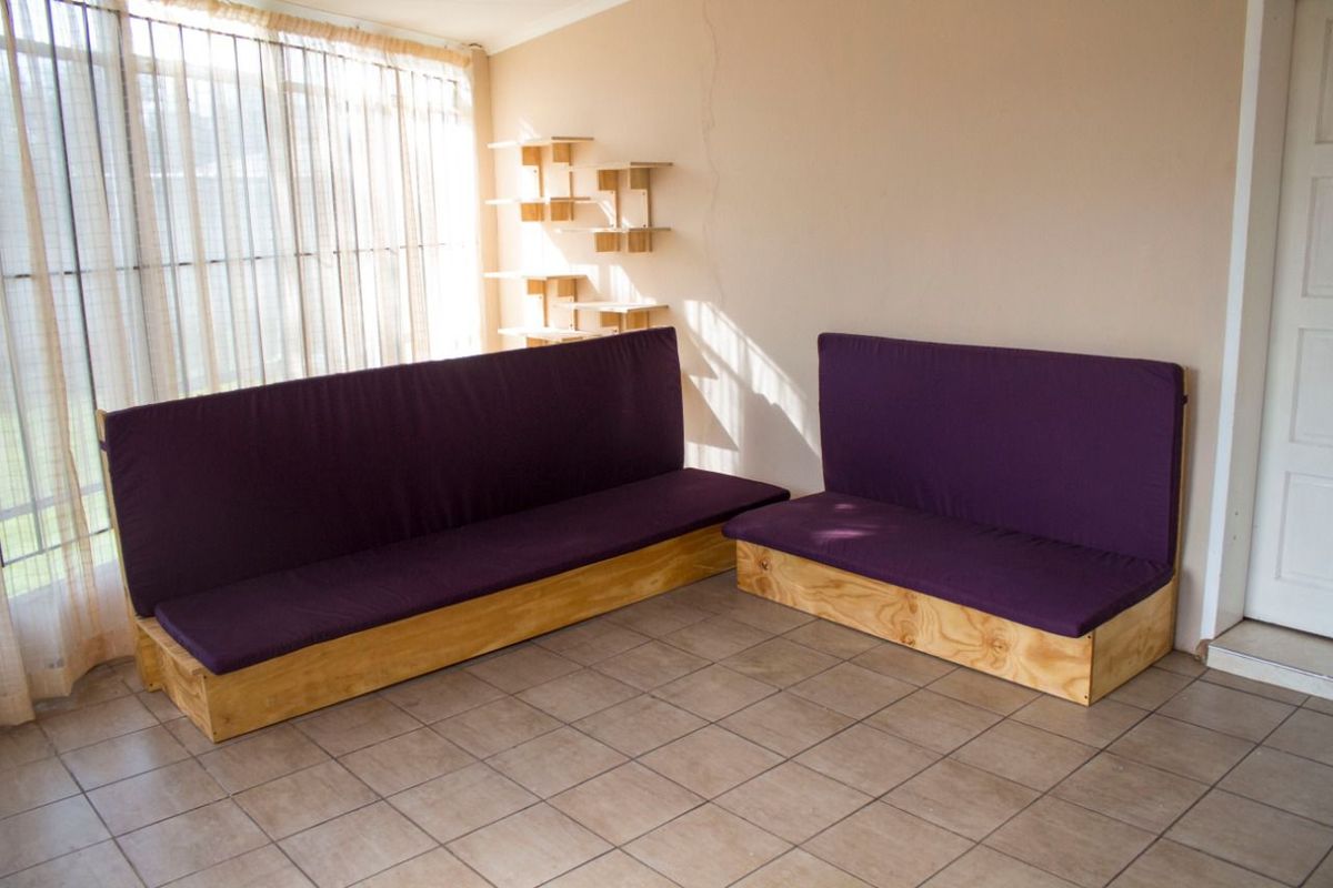A living area featuring tiled flooring, large windows with curtains, and wall-mounted shelving units.