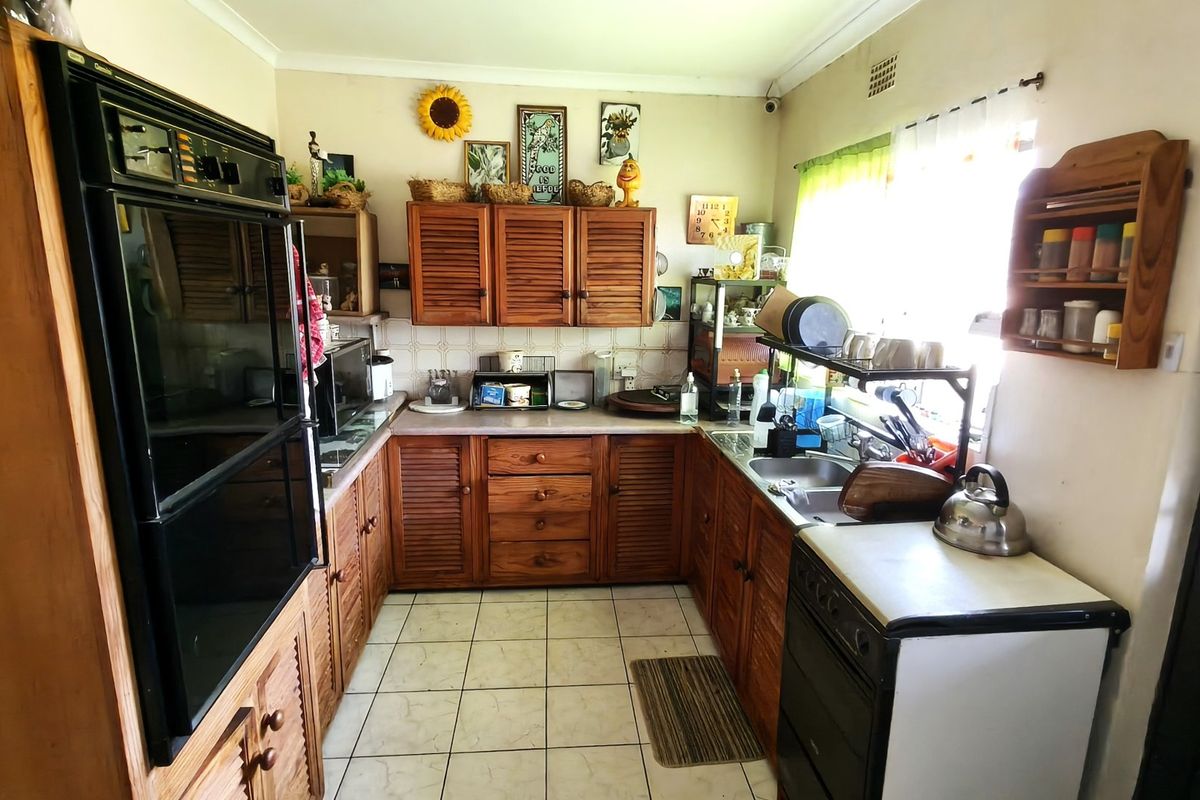 A functional kitchen featuring traditional wooden cabinetry, a double wall oven, and tiled flooring, offering a classic layout with potential for modern updates.