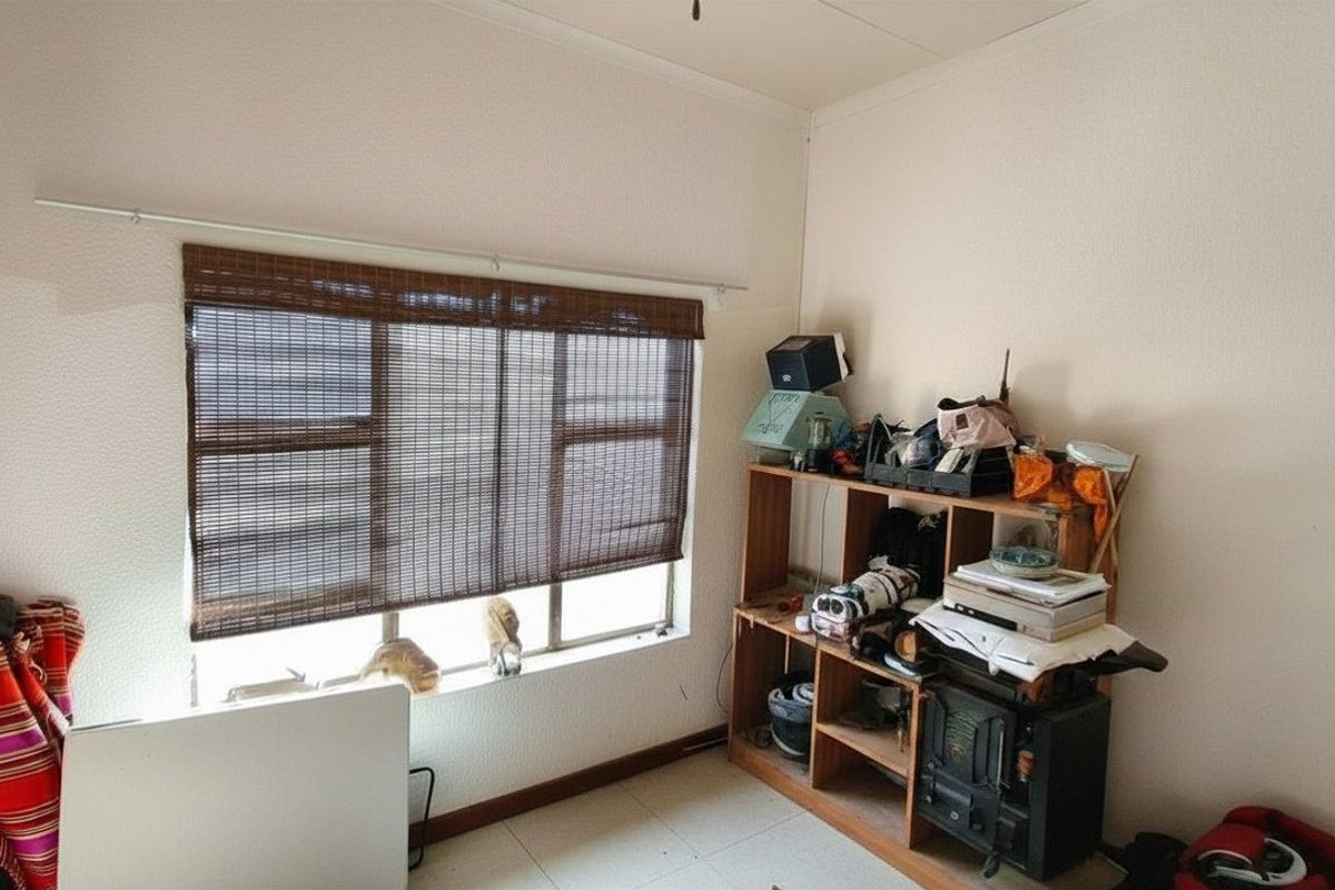 A bedroom featuring tiled flooring and a window with a bamboo blind, offering a functional space ready for personalization.