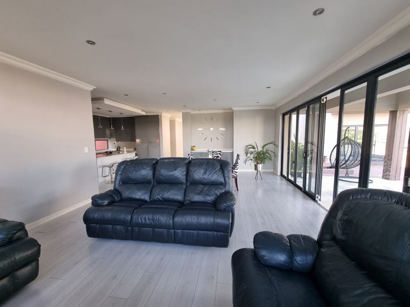 Spacious open-plan living area featuring modern laminate flooring, recessed lighting, and large sliding glass doors providing seamless access to the outdoor patio.