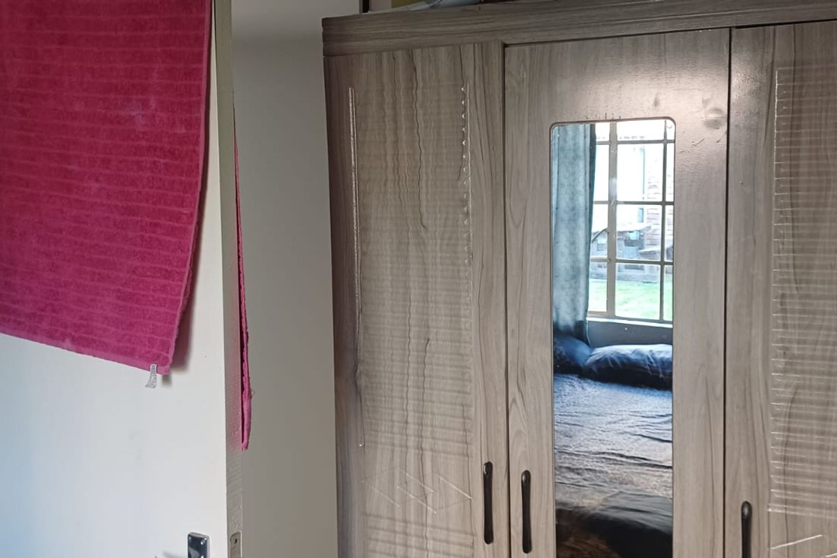 A bedroom interior featuring a window and a large wardrobe.