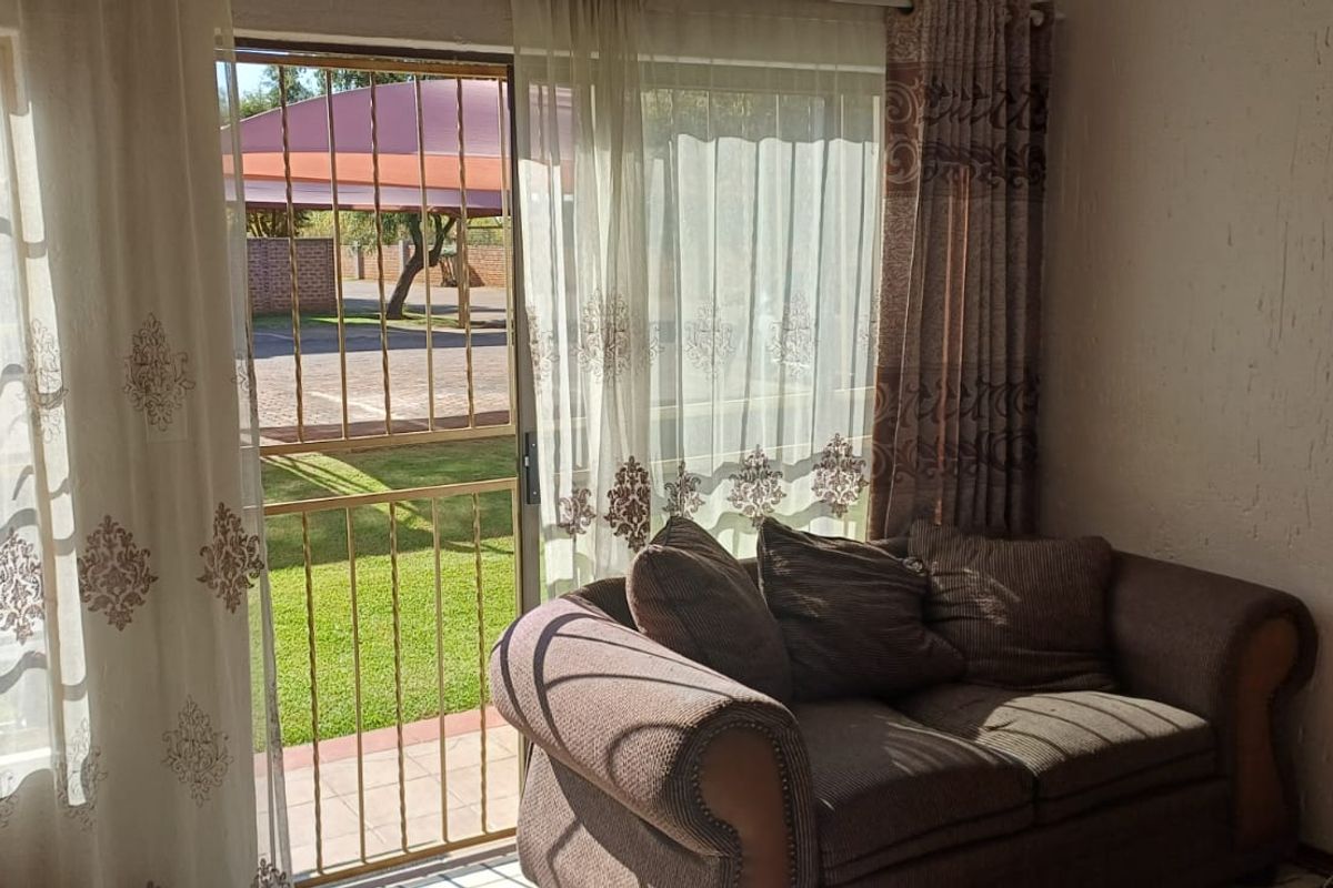 Living room featuring a sliding glass door with security gate, providing direct access to the outdoor area and natural light.