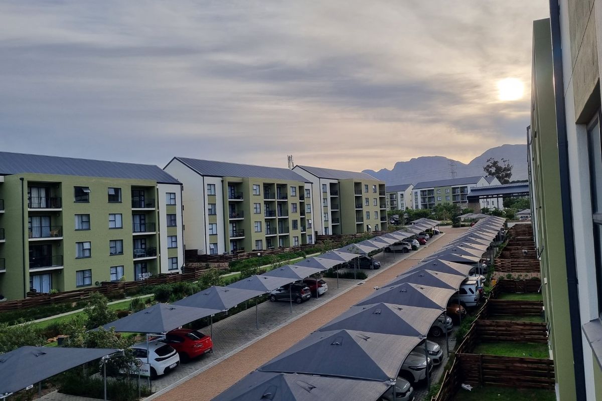 Elevated view of an apartment complex featuring multiple residential blocks, paved driveways, and rows of covered parking bays.