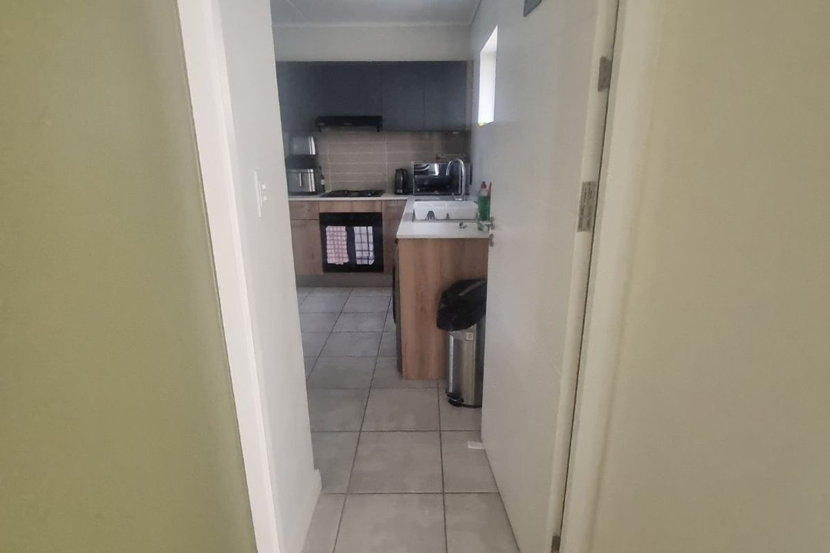 A view through a doorway into a functional kitchen featuring built-in cabinetry, a hob, oven, and tiled flooring.