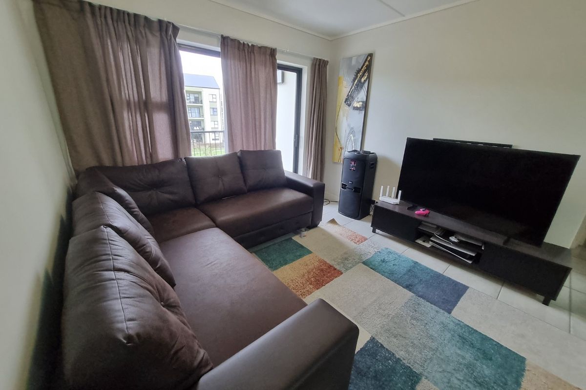 A functional living room featuring tiled flooring and a sliding glass door providing access to the exterior.