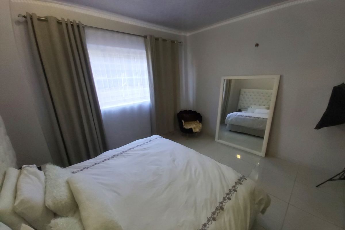 A well-maintained bedroom featuring neutral wall tones, tiled flooring, and decorative crown molding, providing a clean and comfortable living space.