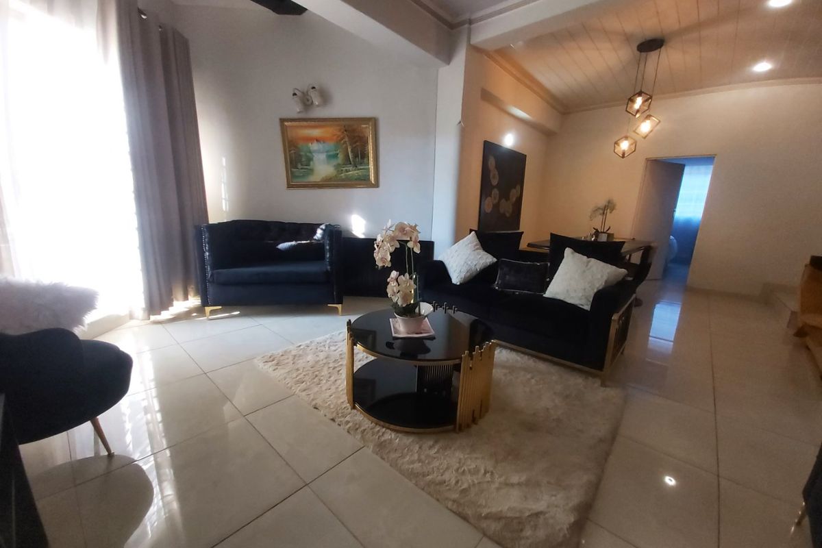 Spacious living area featuring polished tile flooring, modern pendant lighting, and exposed ceiling beams, creating a bright and open atmosphere.