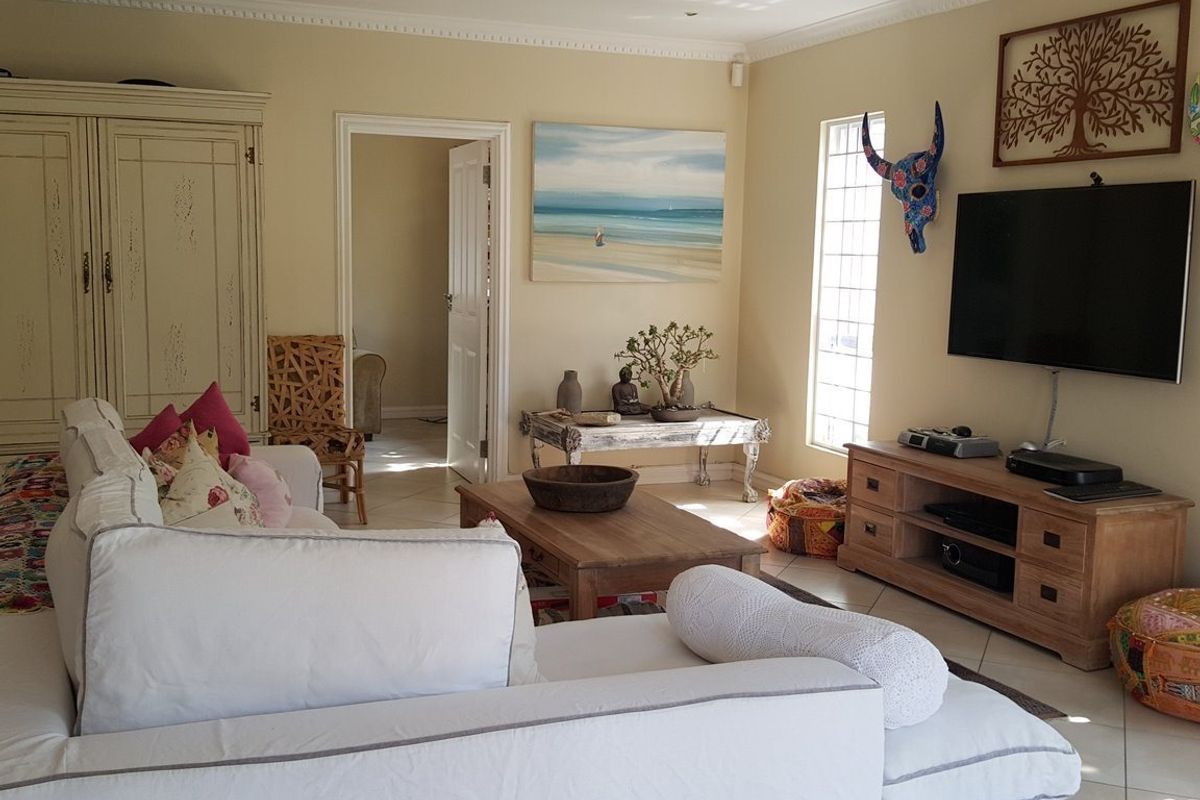 A comfortable living room featuring tiled flooring, crown molding, and security bars on the windows, providing a functional and well-lit space.