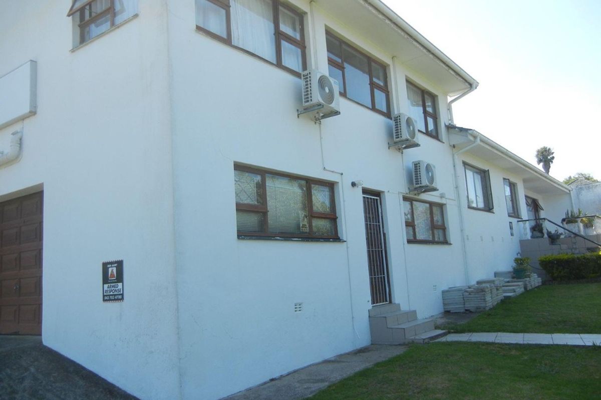 Rear exterior view of the property featuring multiple air conditioning units, security gate, and concrete steps leading to the building.