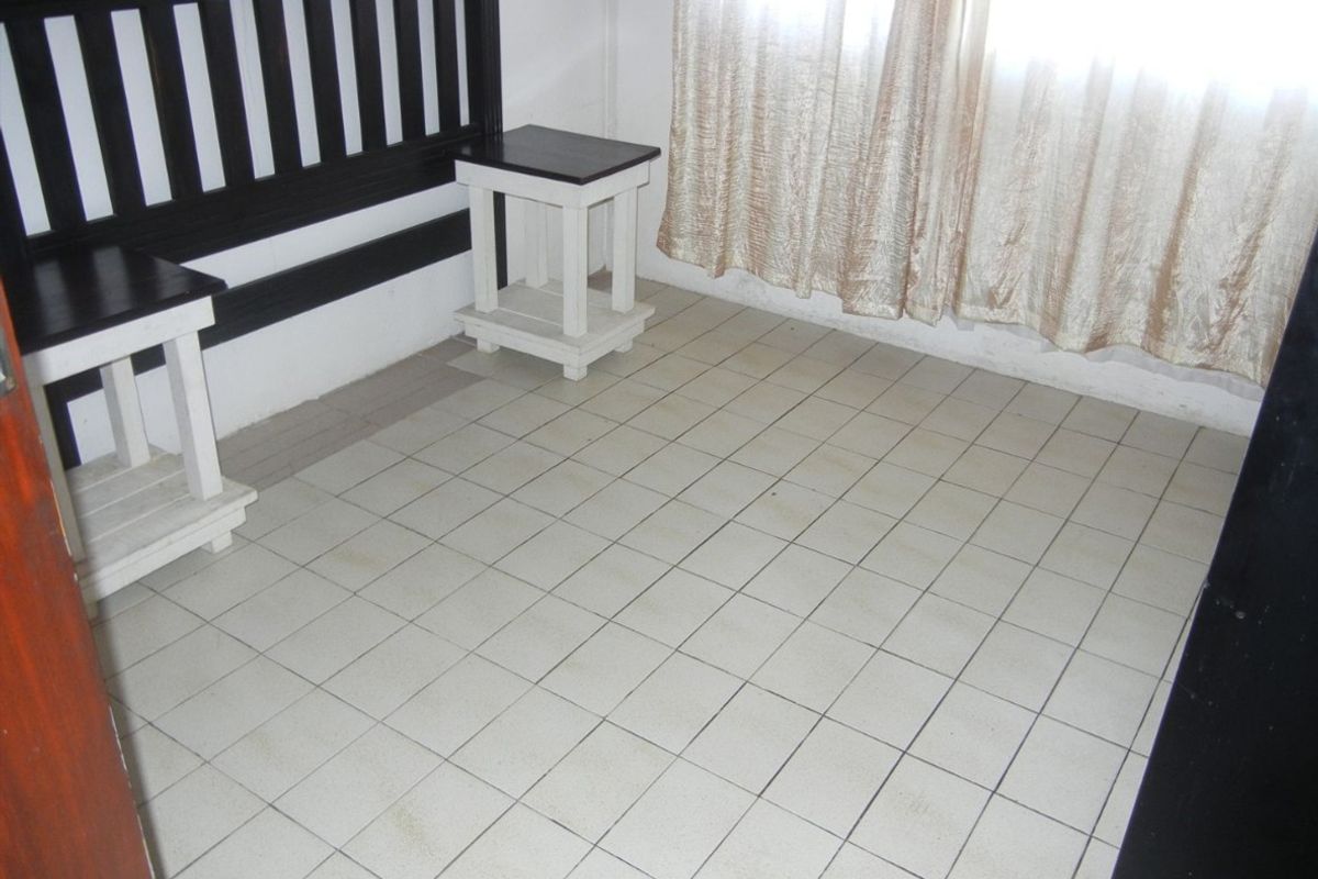 A bedroom featuring tiled flooring and neutral wall finishes, currently requiring maintenance to the floor tiles and grout.