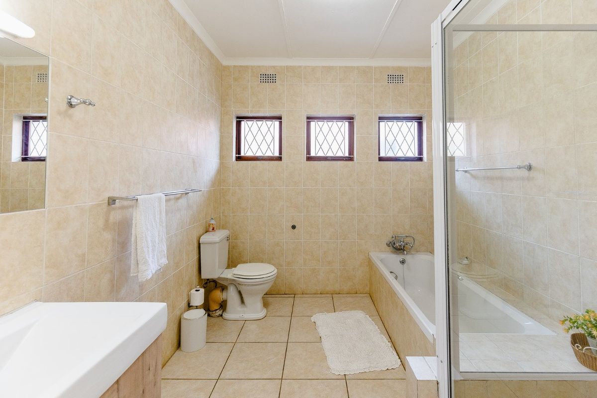 A functional bathroom featuring a bathtub, separate shower enclosure, toilet, and vanity, finished with neutral ceramic wall and floor tiles.