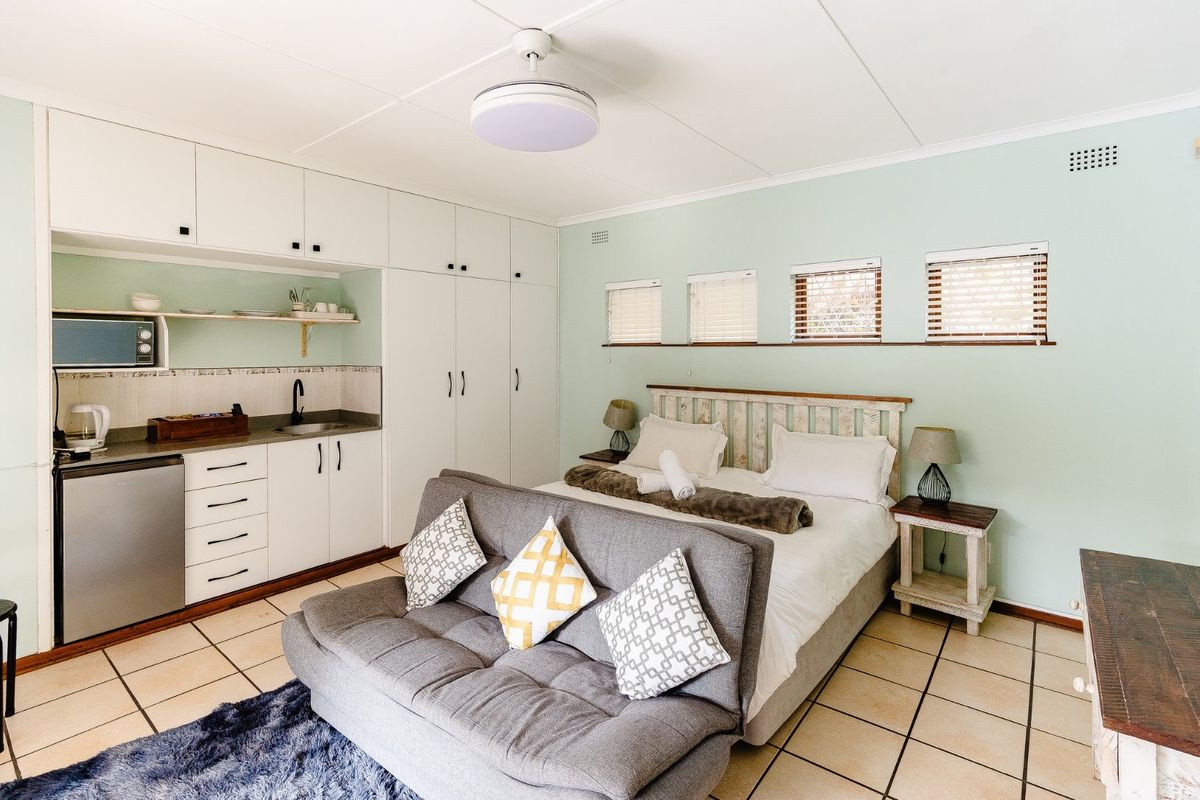 A well-maintained bedroom featuring a kitchenette with built-in cabinetry, tiled flooring, and a ceiling fan, offering a functional and compact living space.