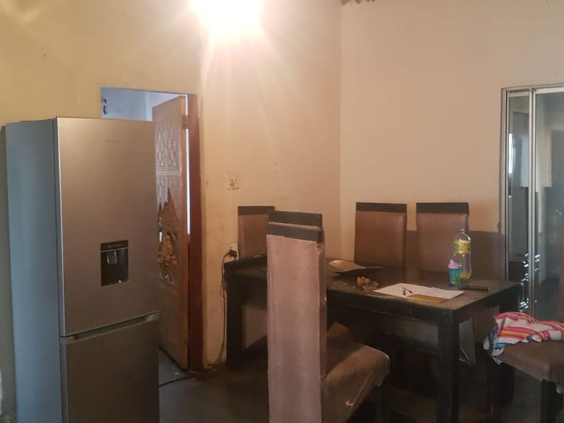 A dining area featuring a sliding door and plain wall finishes, requiring cosmetic updates to improve the overall aesthetic and condition.