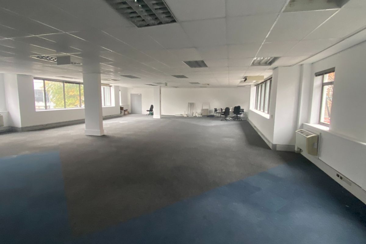 A large, open-plan commercial office space featuring suspended ceilings, recessed lighting, and large windows, currently vacant and ready for custom fit-out.