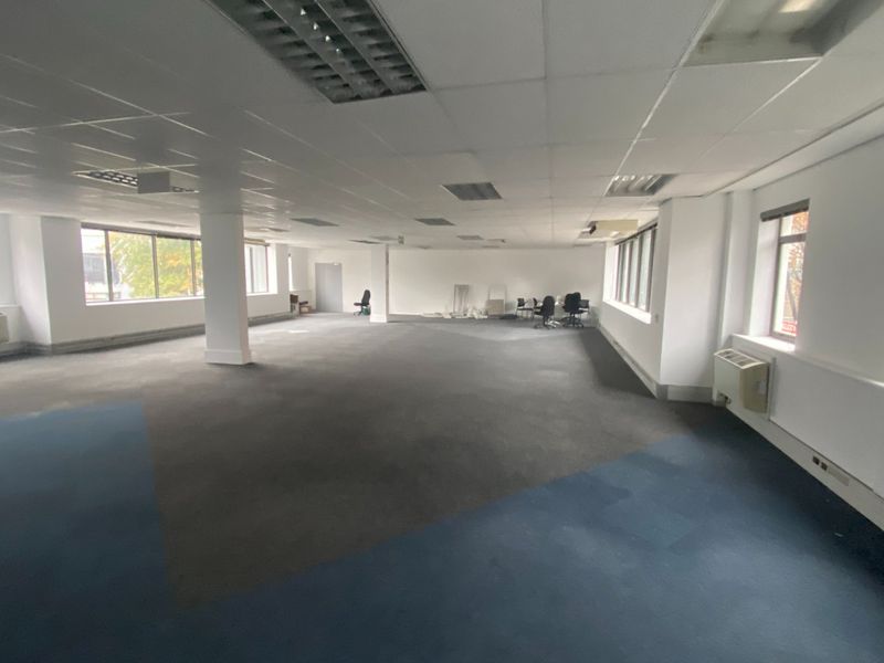 A large, open-plan commercial office space featuring suspended ceilings, recessed lighting, and large windows, currently vacant and ready for custom fit-out.