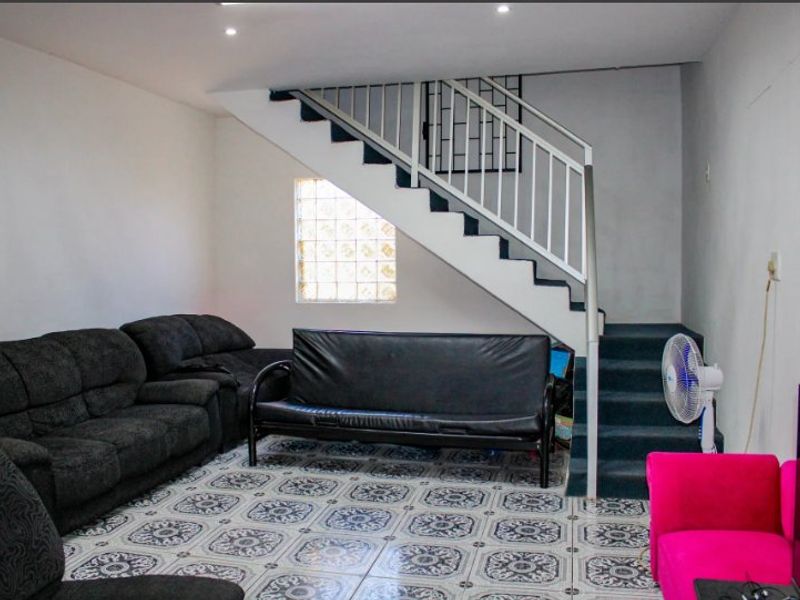 Living room featuring patterned floor tiles, a staircase with a metal railing, and a glass block window providing natural light.