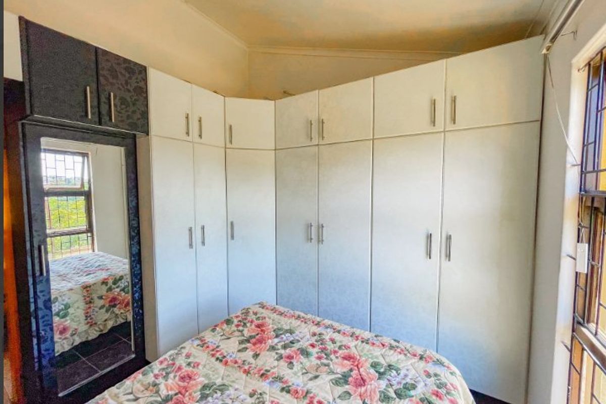 A bedroom featuring extensive built-in cupboards with a mirrored section and security bars on the windows.