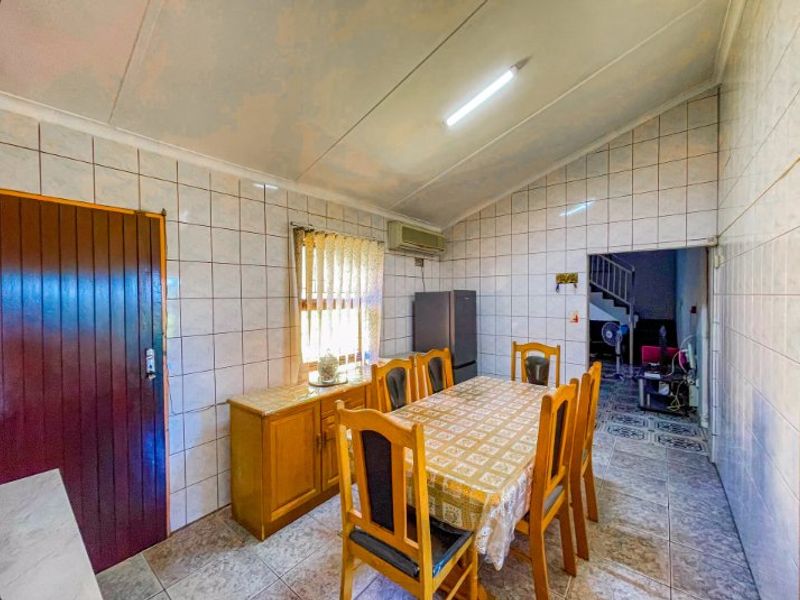 Dining area featuring tiled walls and flooring, with an integrated air conditioning unit and access to an adjacent hallway.