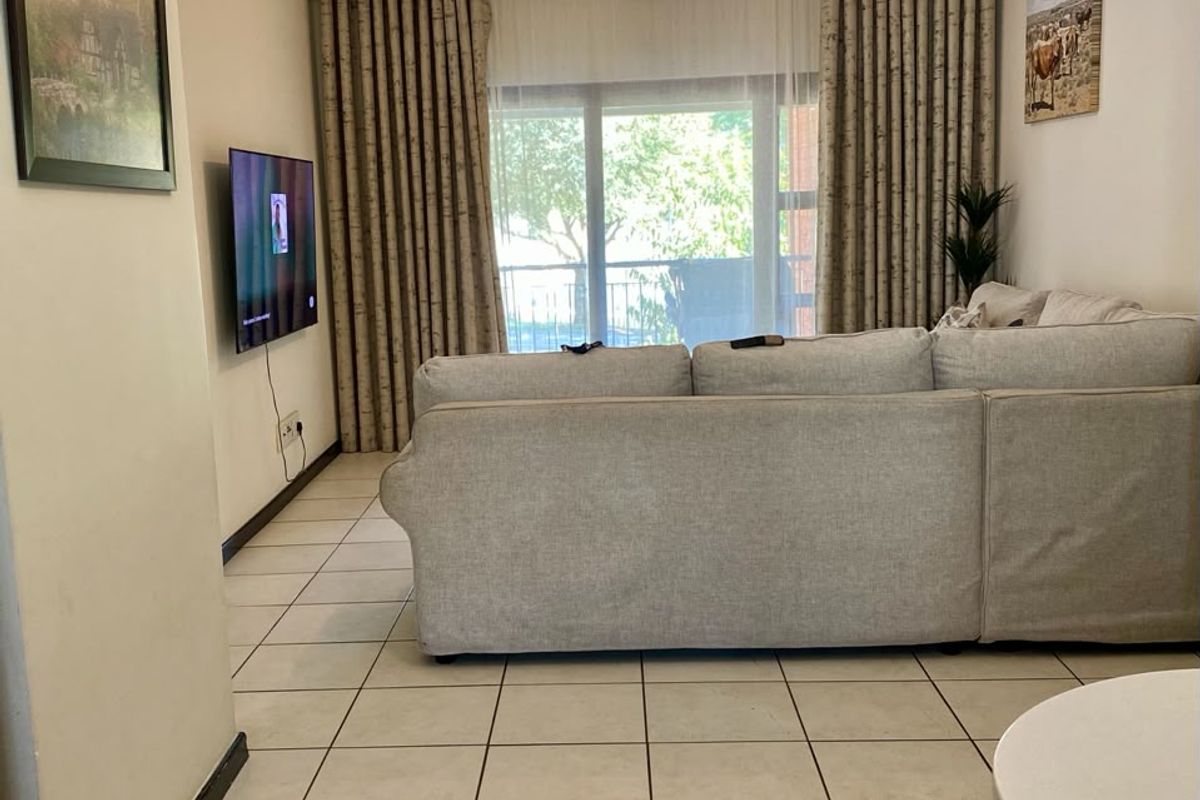 A living room featuring tiled flooring, neutral walls, and a large sliding glass door providing access to an outdoor area.
