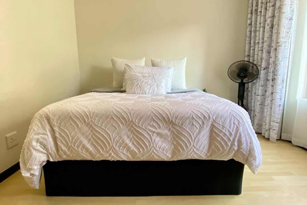 A well-maintained bedroom featuring light-toned laminate flooring, neutral wall finishes, and coved ceiling detailing, providing a clean and comfortable living space.
