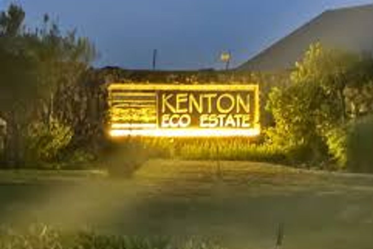 Entrance signage for Kenton Eco Estate featuring illuminated lettering and landscaped surroundings at dusk.