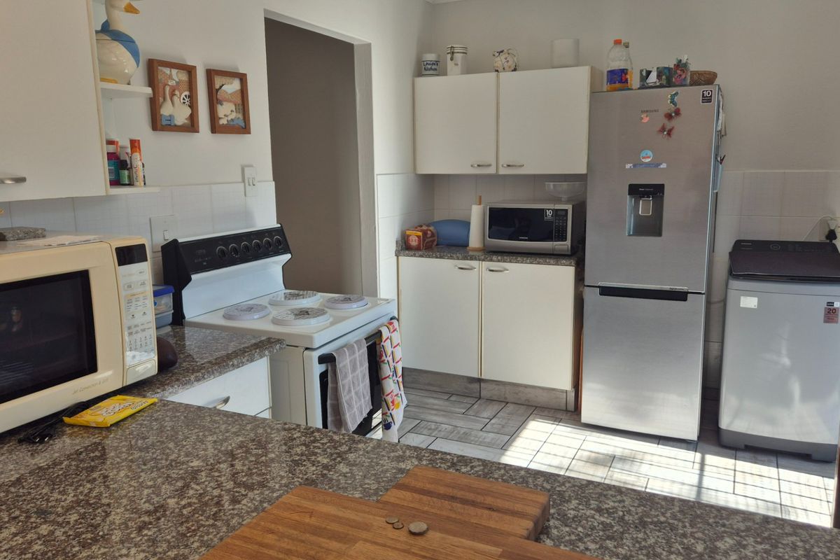 A functional kitchen featuring granite countertops, white cabinetry, tiled flooring, and a tiled backsplash, providing a practical workspace for daily cooking.