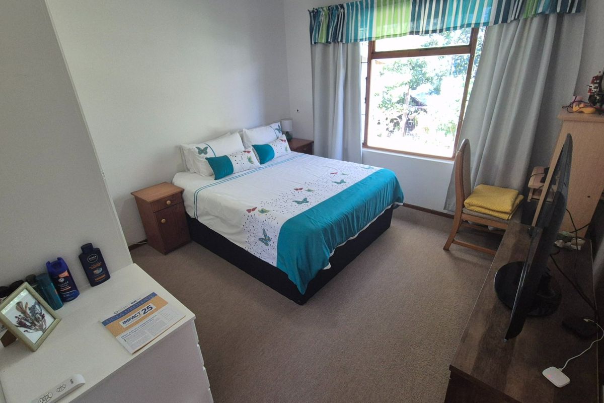 A functional bedroom featuring carpeted flooring and a large window that provides natural light.