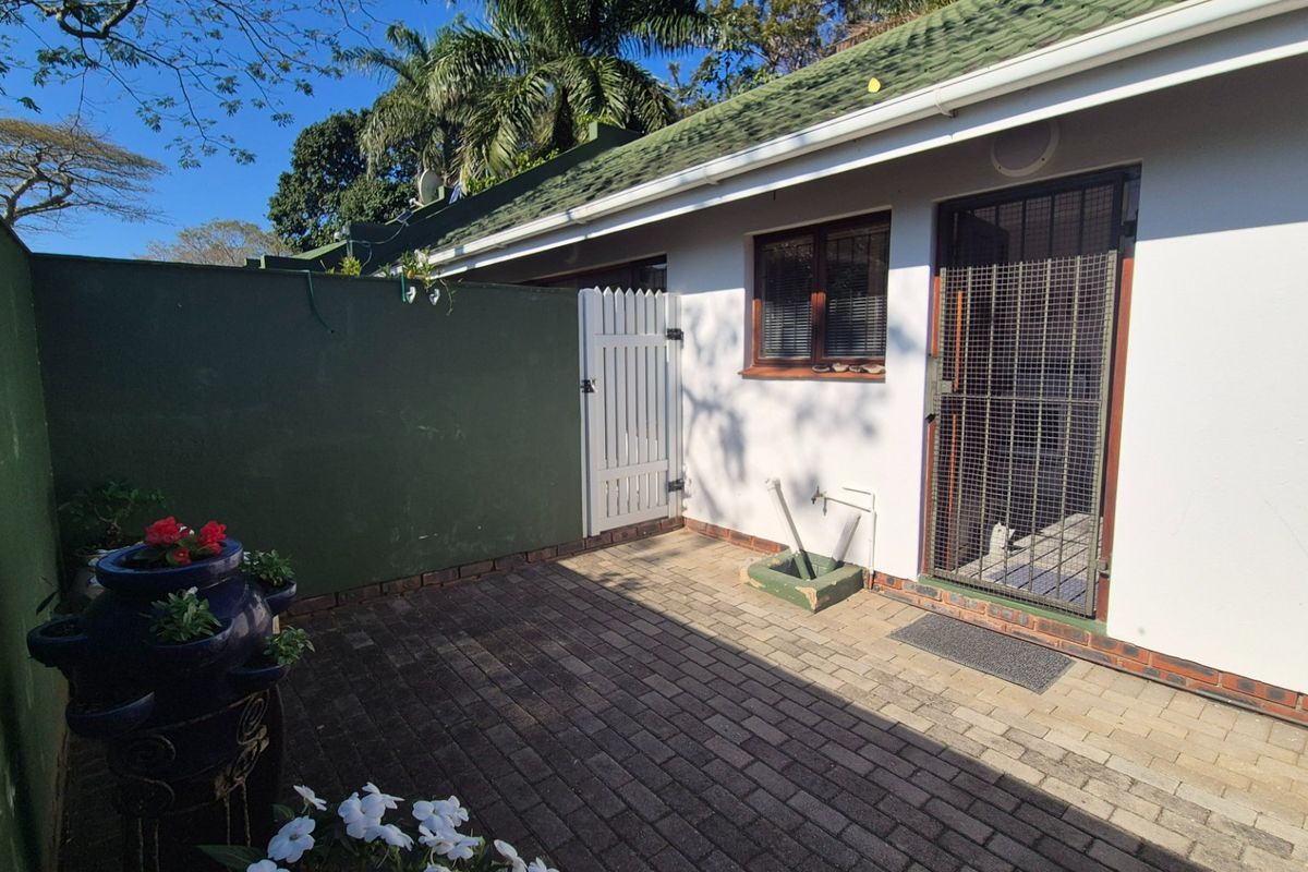 A private paved rear courtyard featuring a security gate, boundary wall, and external plumbing connection, providing a functional outdoor space.