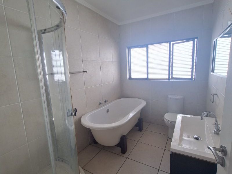 A functional bathroom featuring a freestanding bathtub, a curved glass shower enclosure, a vanity unit with a basin, and a toilet.