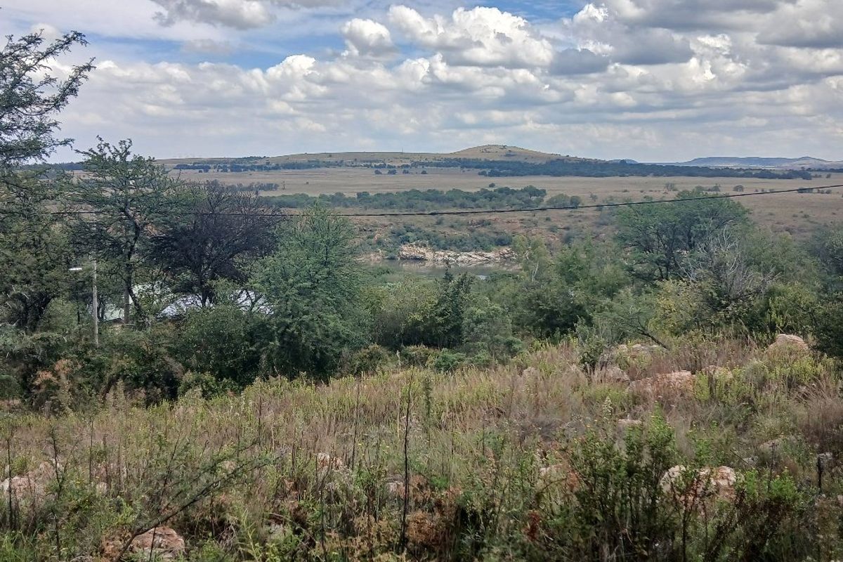 A scenic view of the natural landscape featuring rolling hills, native vegetation, and a river in the distance.