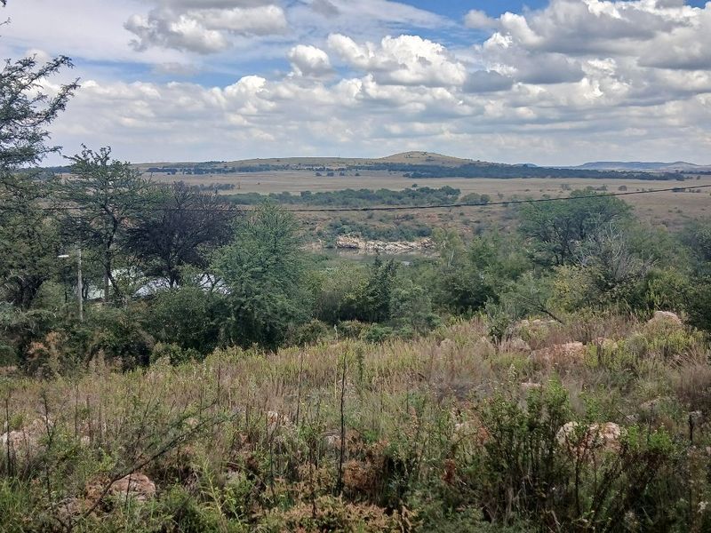 A scenic view of the natural landscape featuring rolling hills, native vegetation, and a river in the distance.