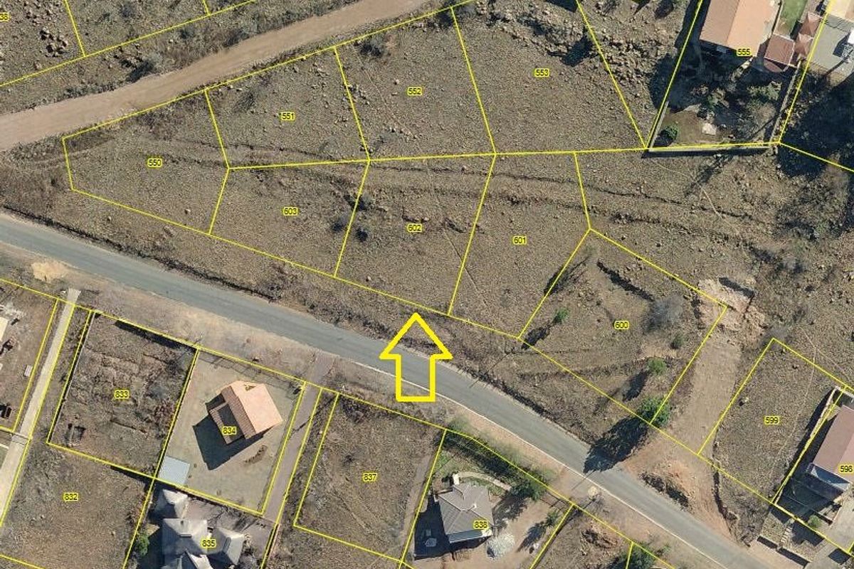 Aerial view of a vacant residential plot with marked boundaries, situated in a developed neighborhood with access to local road infrastructure.