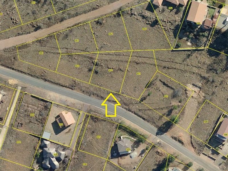 Aerial view of a vacant residential plot with marked boundaries, situated in a developed neighborhood with access to local road infrastructure.