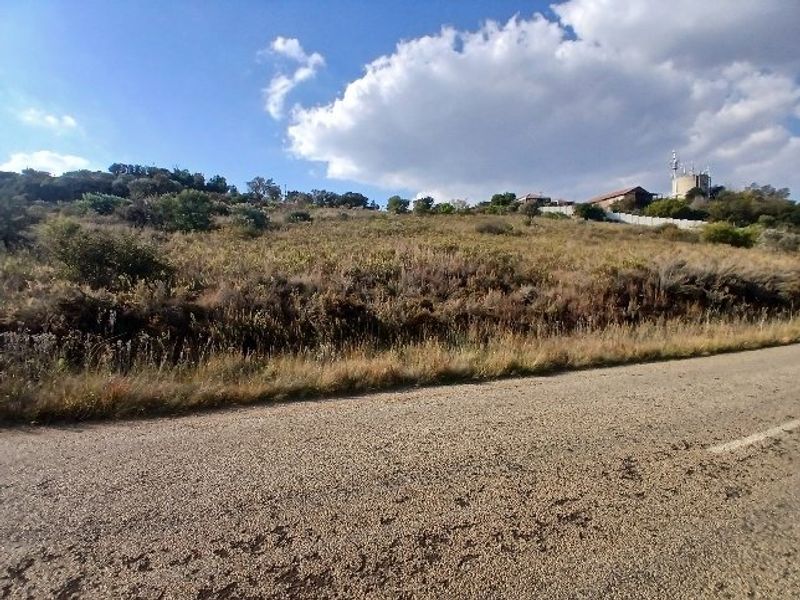 A view of an undeveloped residential plot of land from the adjacent asphalt road.