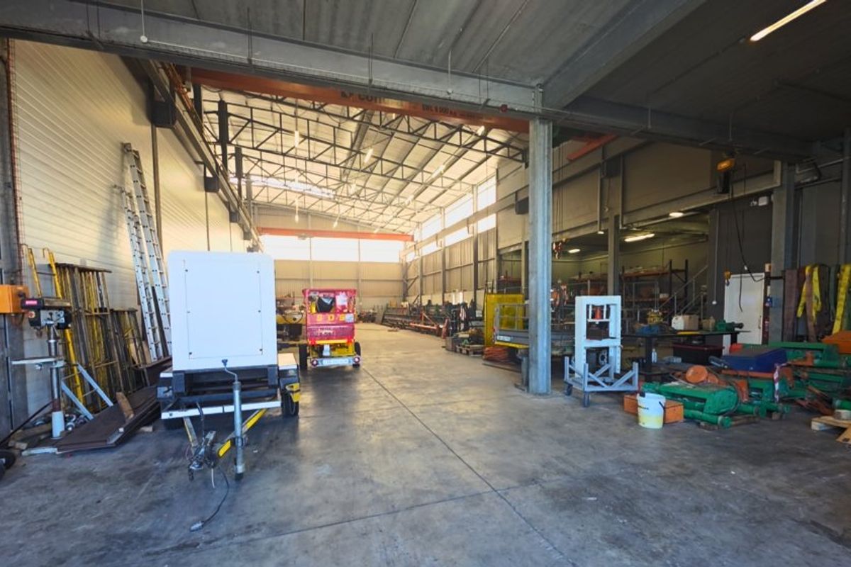Spacious industrial warehouse featuring a steel portal frame, concrete flooring, and an overhead crane, suitable for various commercial or storage operations.