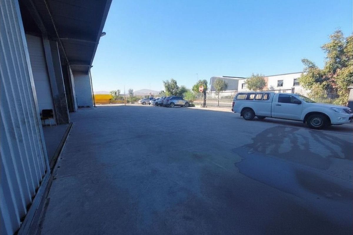 A spacious commercial concrete yard area featuring metal cladding walls and roller shutter access, suitable for industrial operations or vehicle maneuvering.