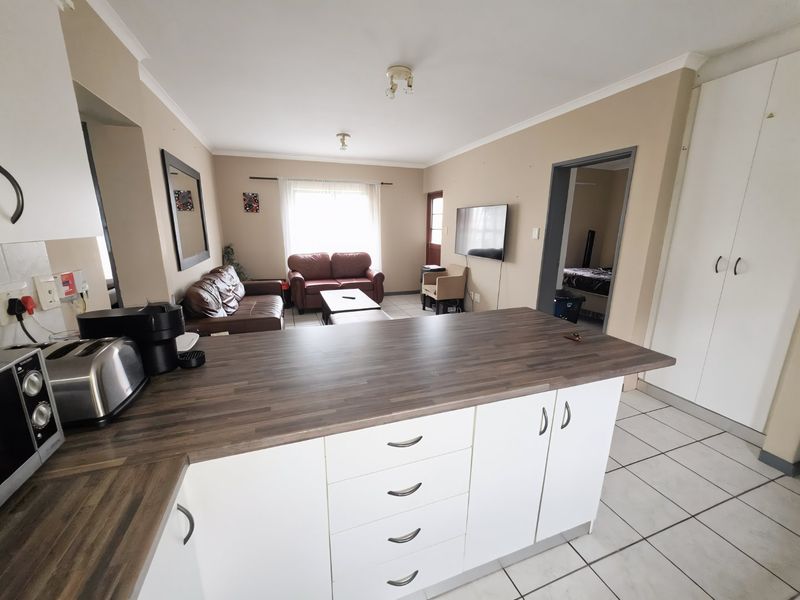 Open-plan living area featuring a kitchen island with laminate countertops, tiled flooring, and built-in cabinetry, seamlessly connecting to the lounge space.