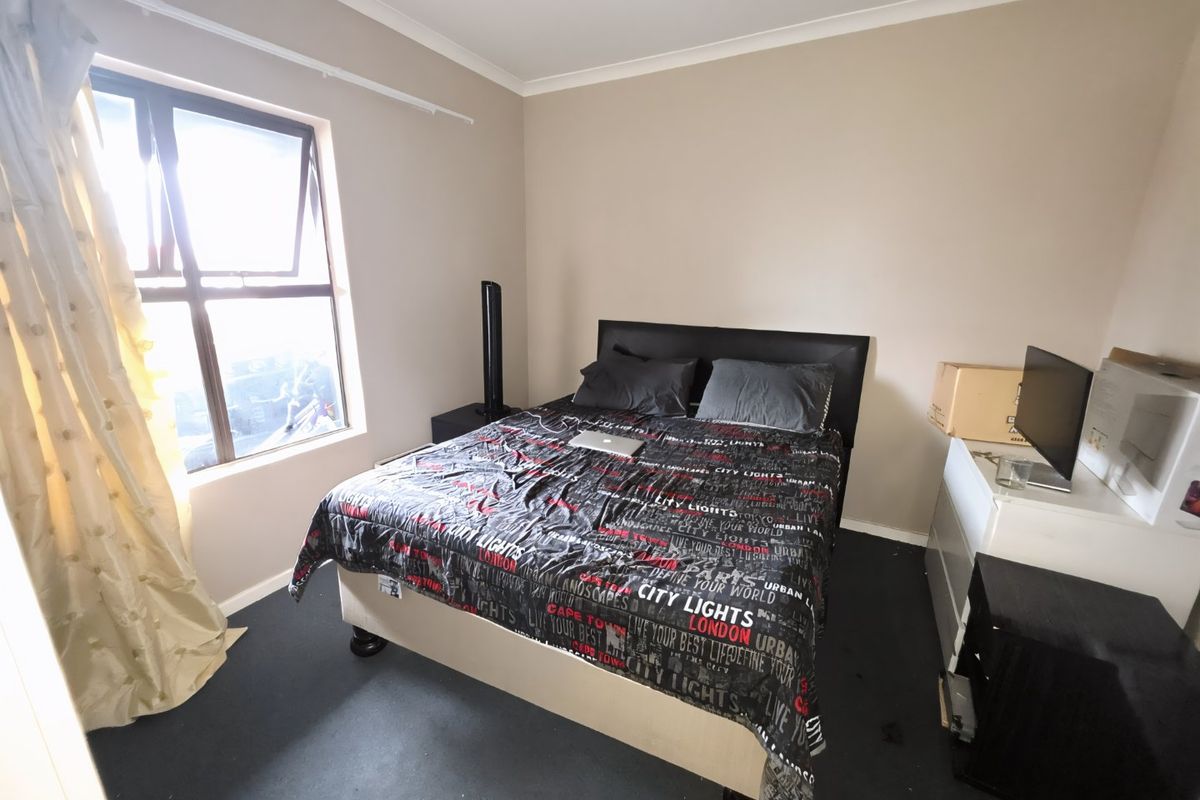 A standard bedroom featuring a casement window and neutral wall finishes, providing a functional space for rest.