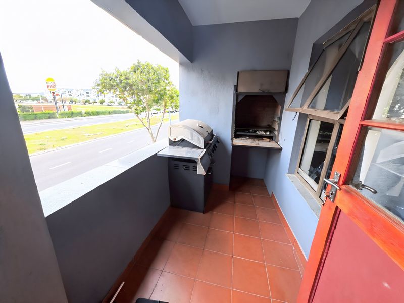 Covered balcony featuring a built-in braai, tiled flooring, and direct access to the living area, offering an outdoor space for relaxation.